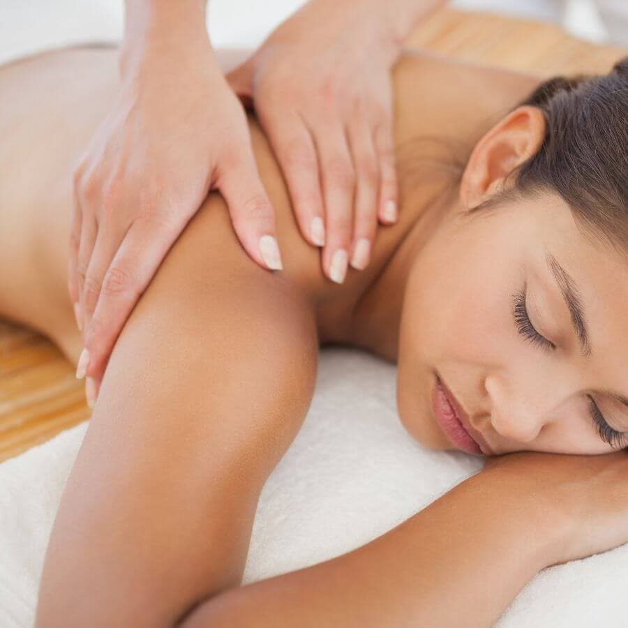 A woman is receiving a back massage in a calm setting.