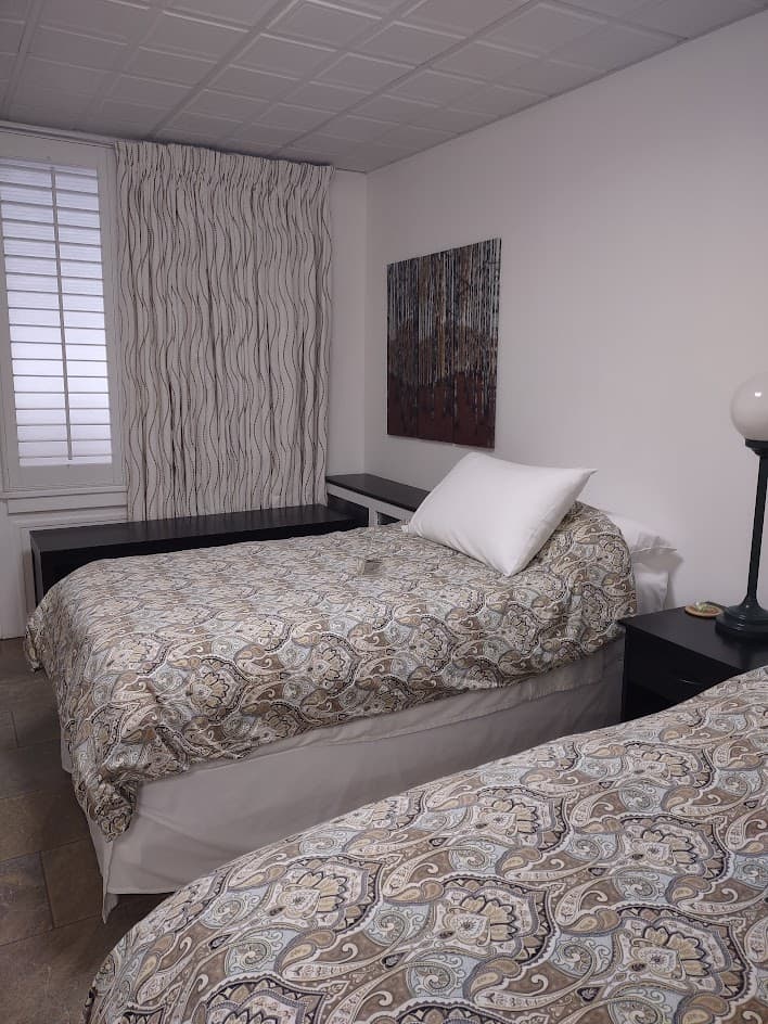 A cozy bedroom featuring two twin beds with patterned bedding and a small bedside lamp.