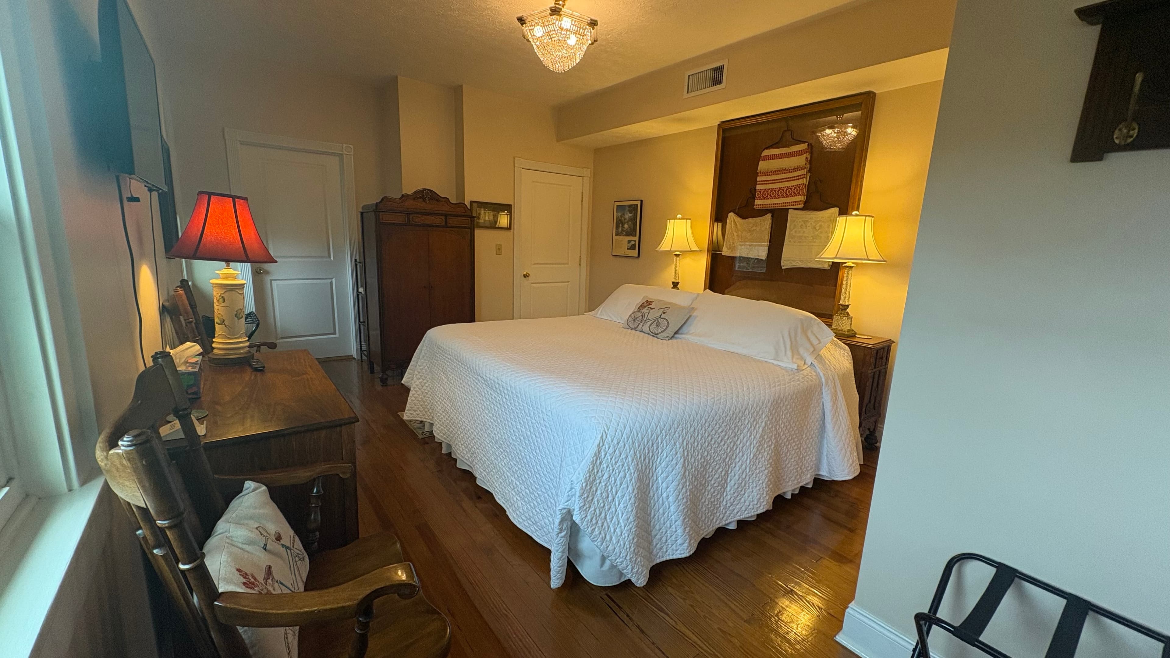 Cozy bedroom with a large bed, wooden furniture, and warm lighting.