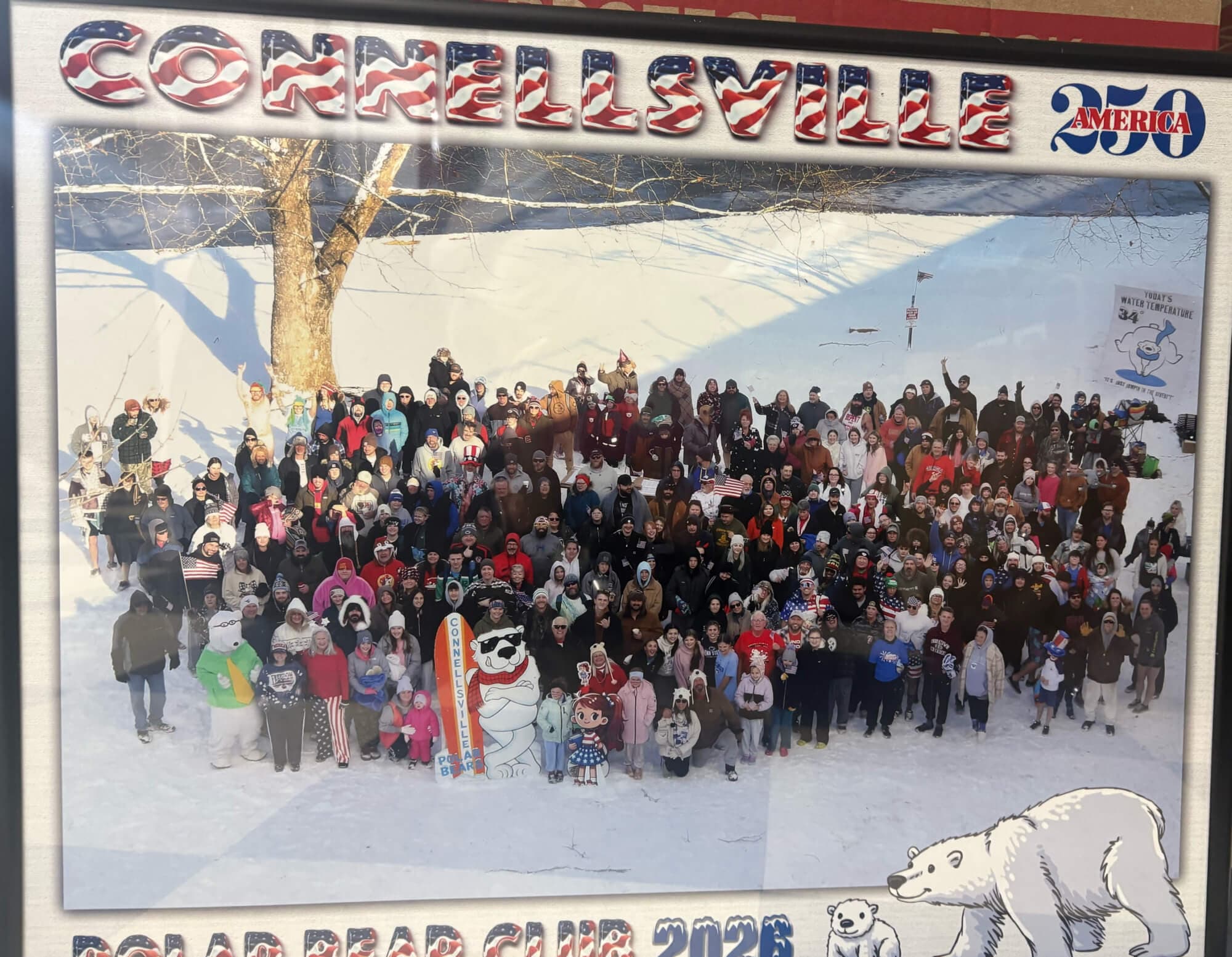 A large group of people, dressed warmly, gathers in the snow for the Connellsville Polar Bear Club event.