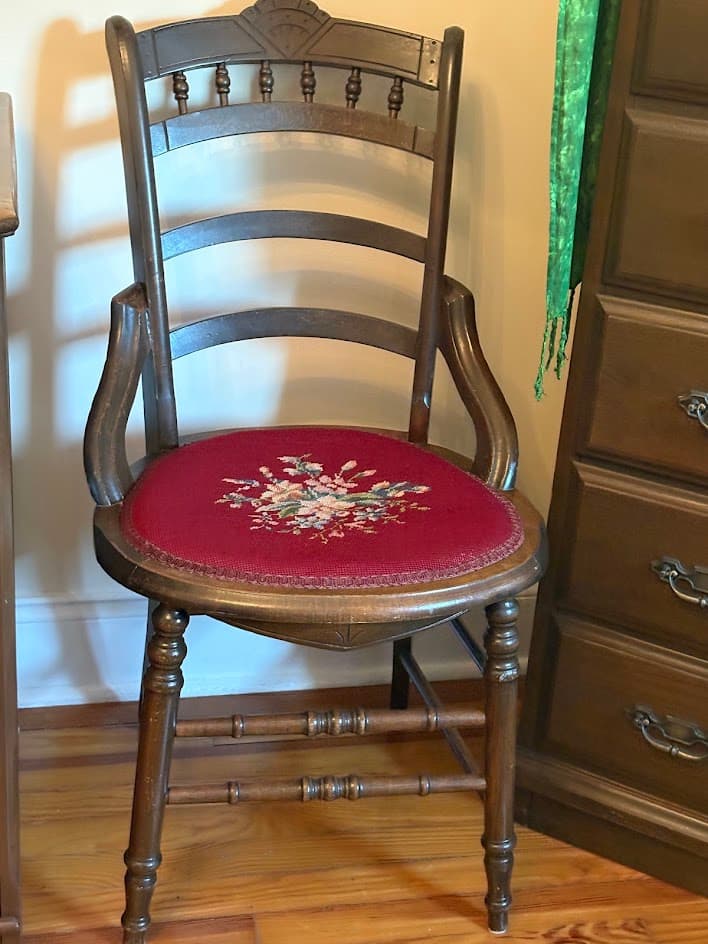 walnut wood antique chair with floral needlepoint on red background